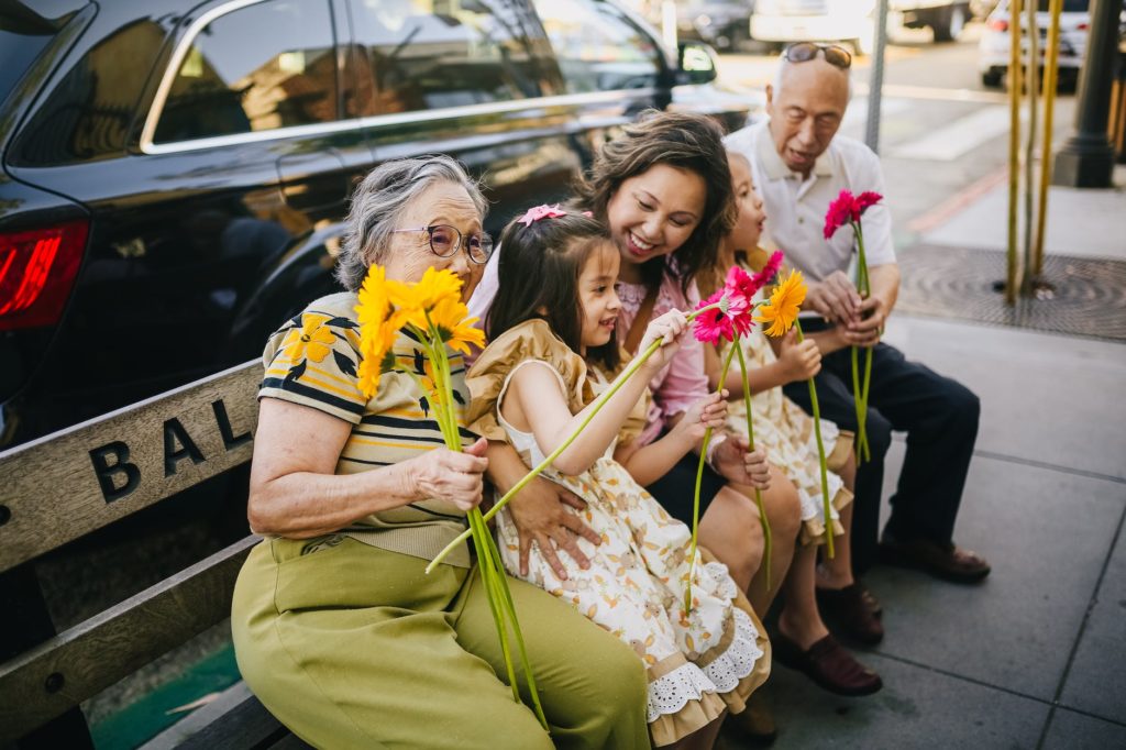 a happy asian family sitting on a bench