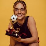 a smiling woman holding a trophy