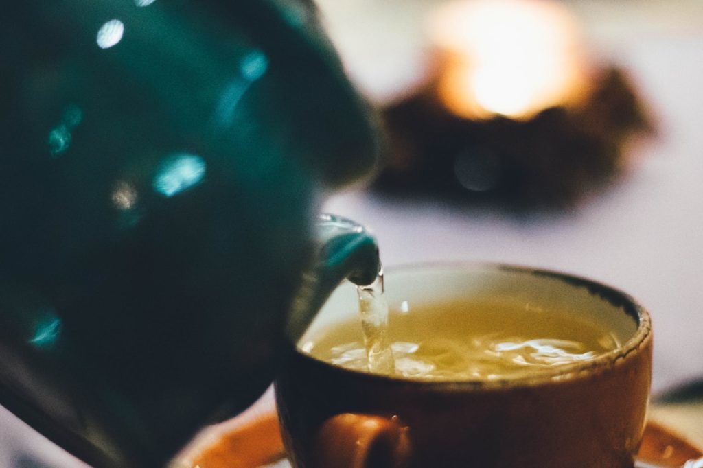 person pouring liquid into brown ceramic cup