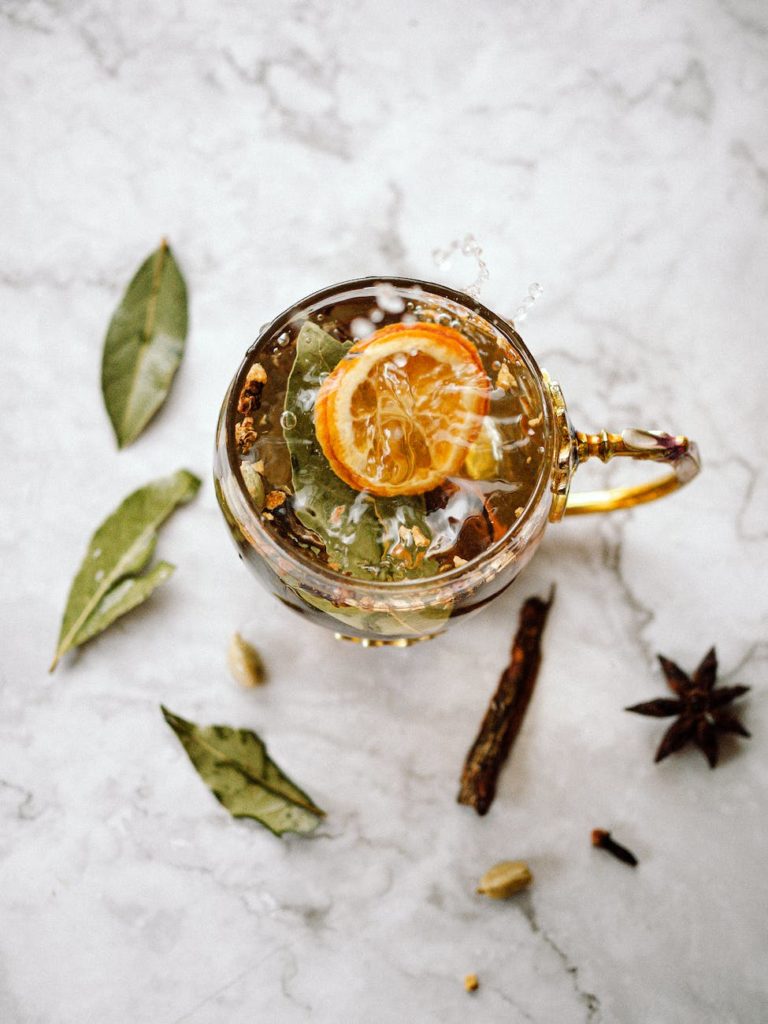 a cup of tea with herbs lying next to it