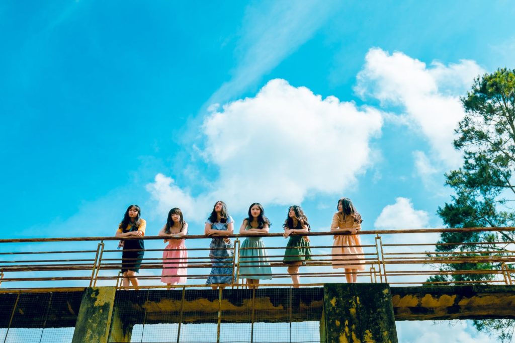 six women wearing dress leaning on bridge rail