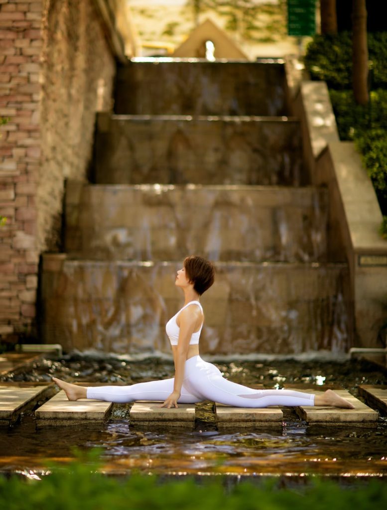 woman doing a split on stepping stones over a river