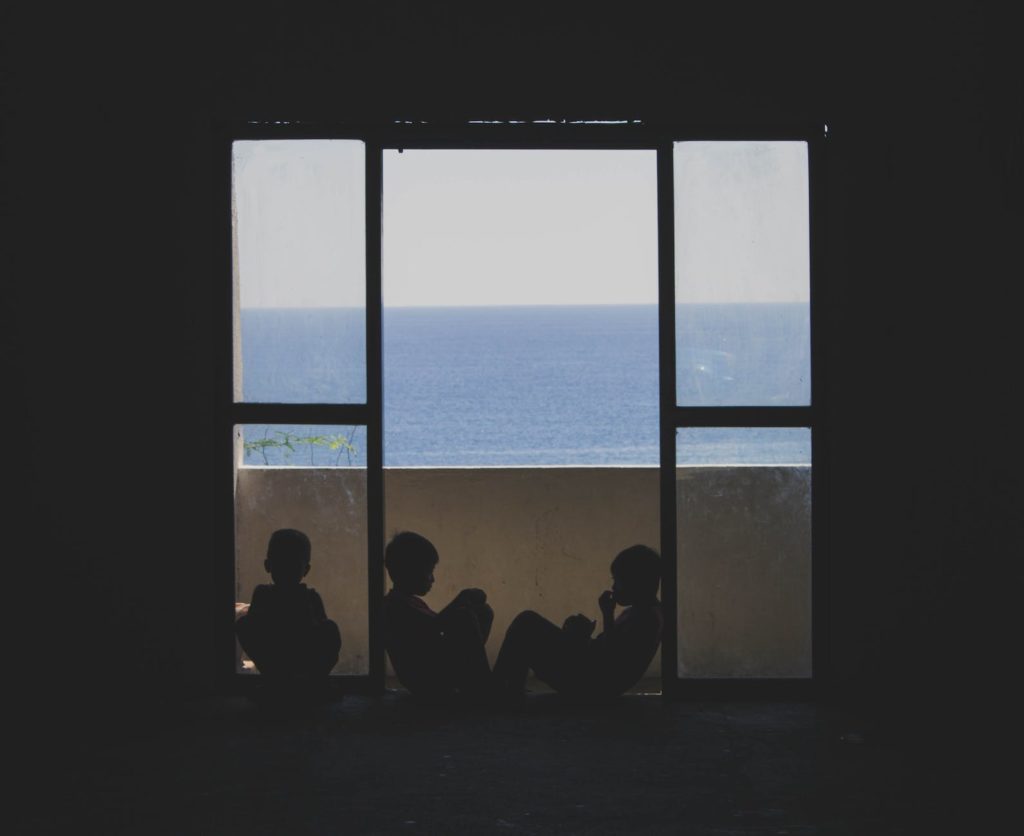 silhouettes of children in the window with view on the sea