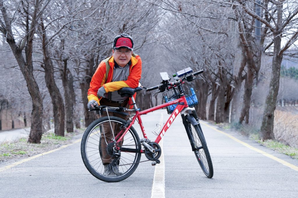 old man with bike on road in winter countryside