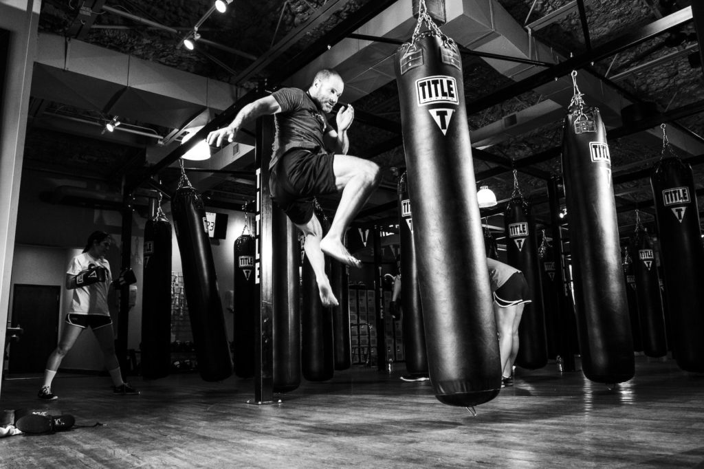 man kicking heavy bag