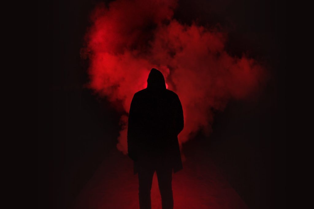 silhouette of man standing against black and red background