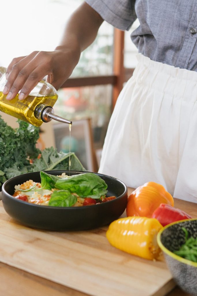 photo of woman pouring liquid on vegetable