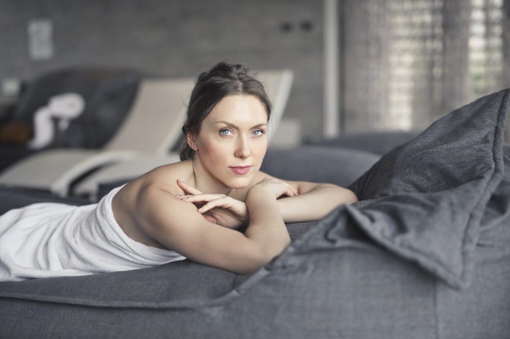 woman covered in towel lying on bed