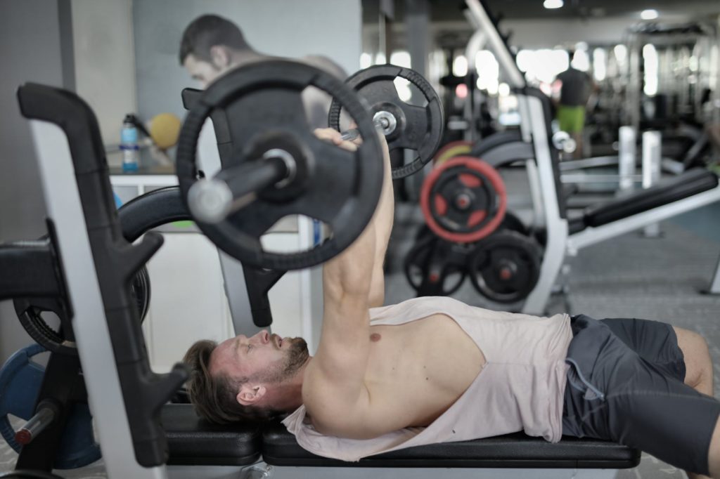 strong sportsman doing bench press during workout in modern gym