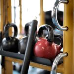 several kettlebells on metal bar in gym