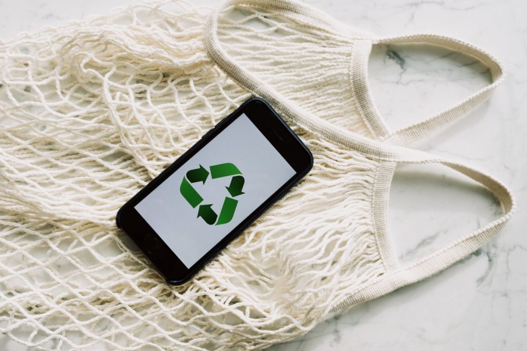 eco friendly white mesh bag with smartphone placed on marble table