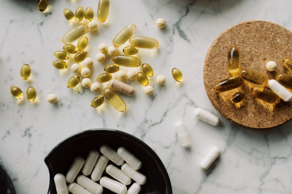 variety of capsules and dragees on white marble countertop in studio