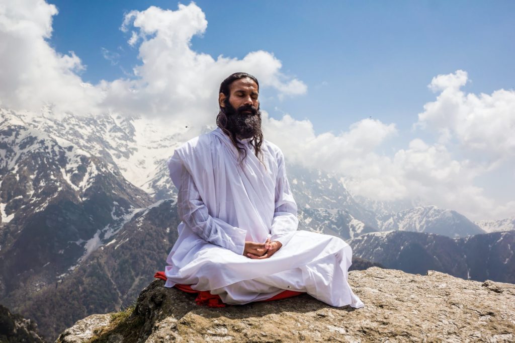 a man in white thobe meditating on the mountain top