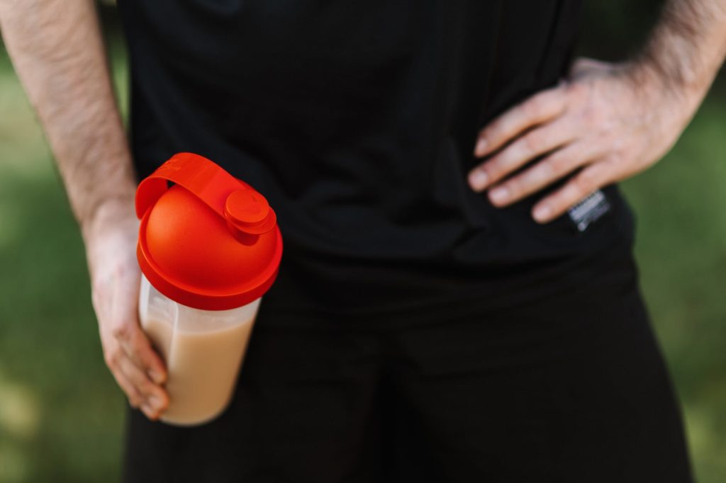 man holding a tumbler with hand on waist