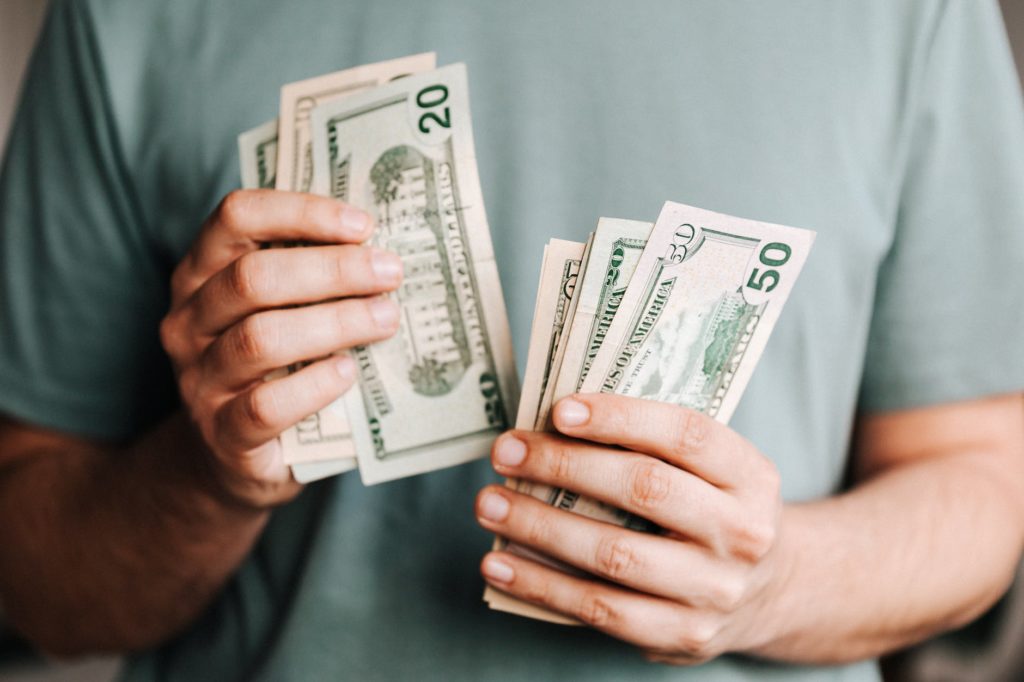 crop man counting dollar banknotes