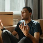 man in black crew neck t shirt sitting on brown sofa