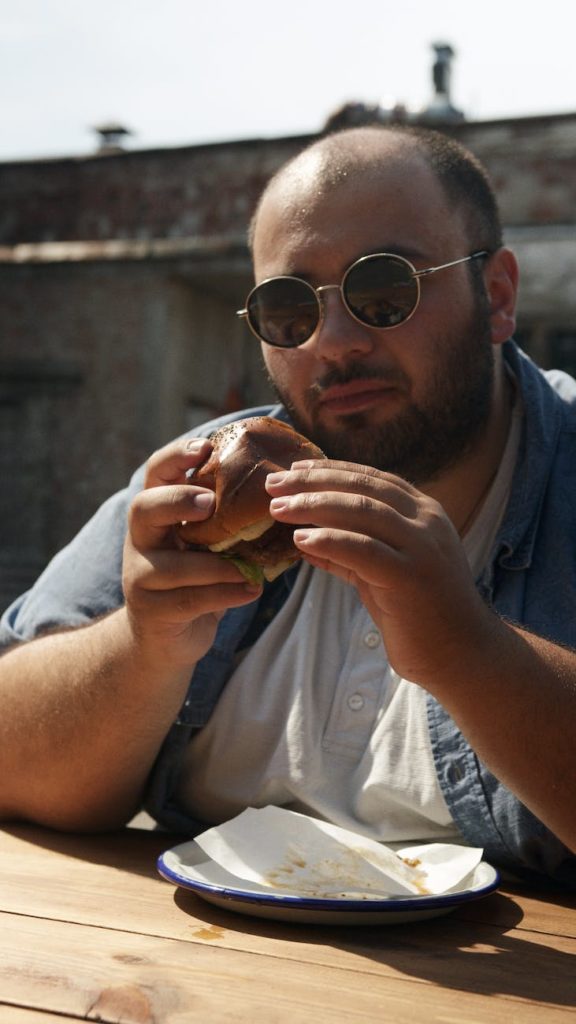 man wearing sunglasses eating hamburger