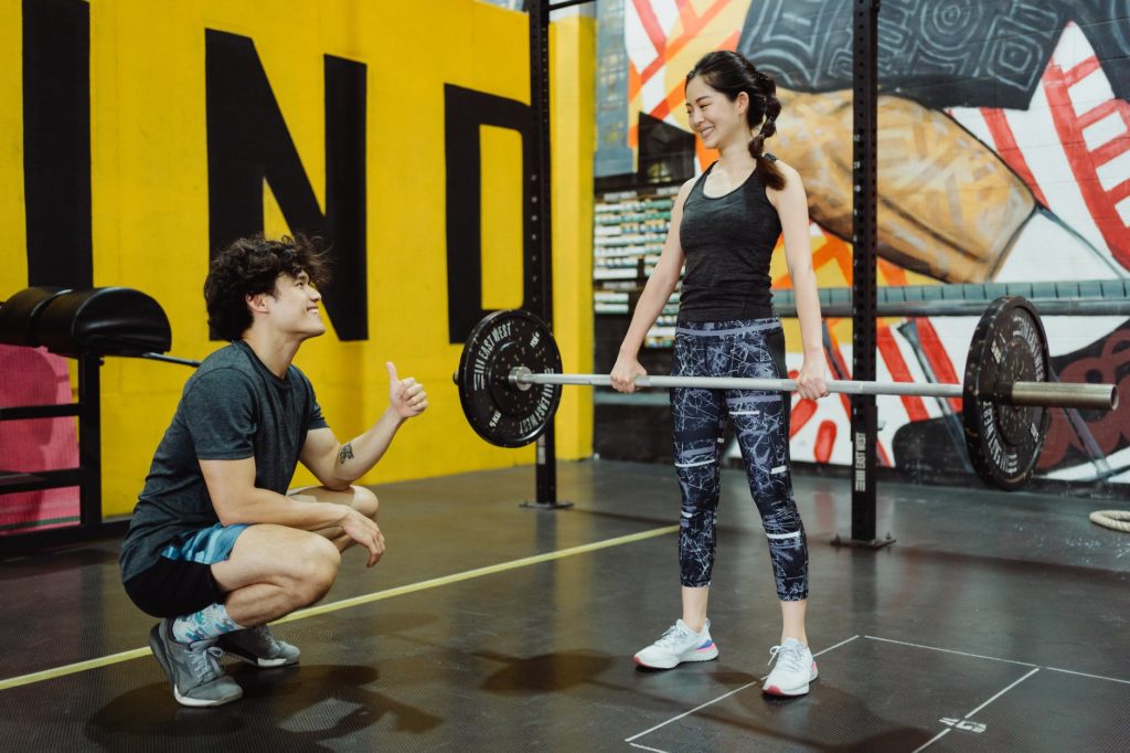 young athletes lifting weights at gym with a mural