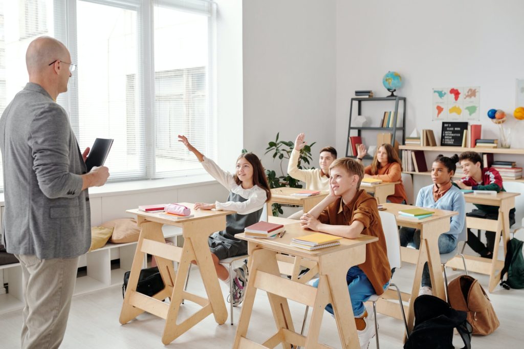 students raising their hands in the classroom