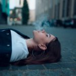 a woman smoking while lying on the road