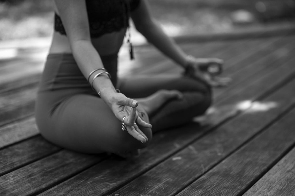 grayscale photo of woman in black tank top and white shorts sitting on wooden floor