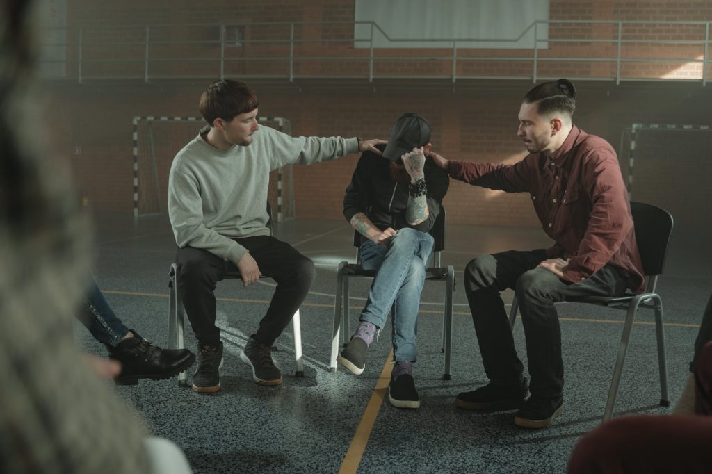 men consoling a member of a group therapy