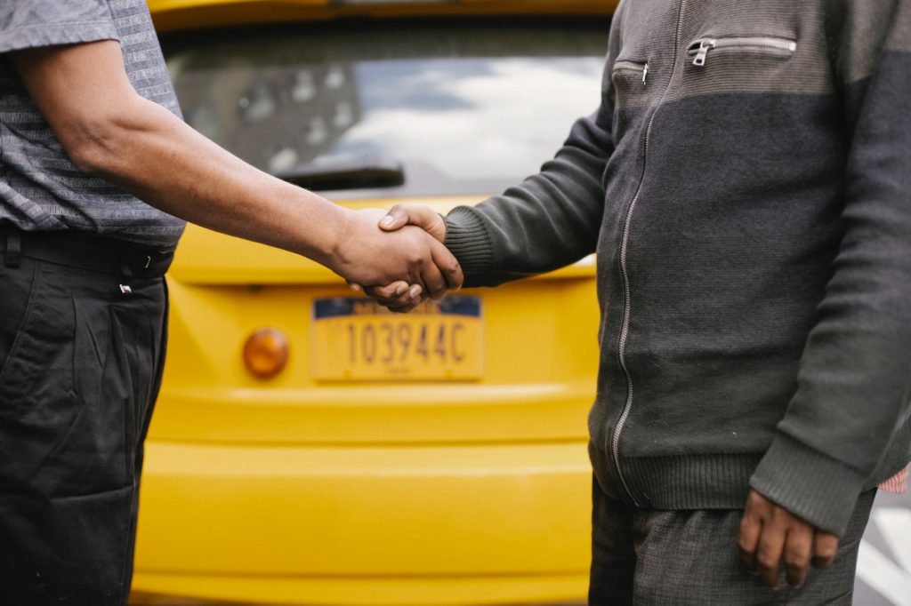 ethnic men shaking hands near taxi