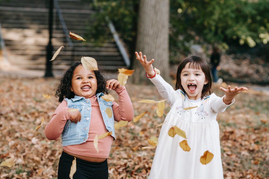 happy kids throwing foliage in park