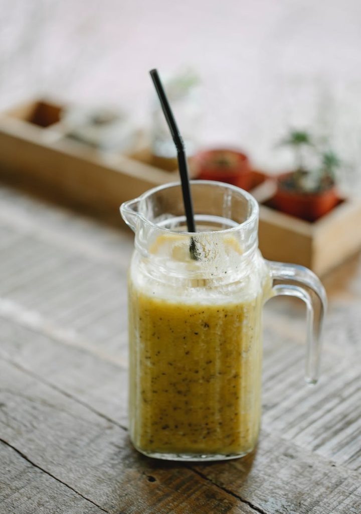 delicious banana smoothie in carafe with straw