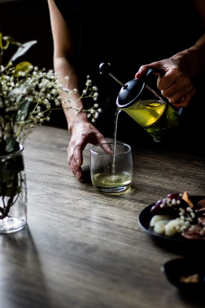 a person pouring yellow liquid in the glass