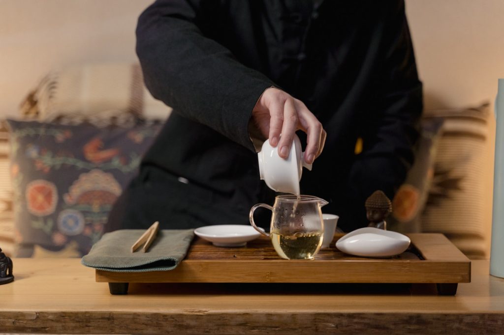 person pouring tea in glass teapot