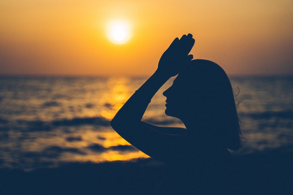 silhouette of woman standing against sunset