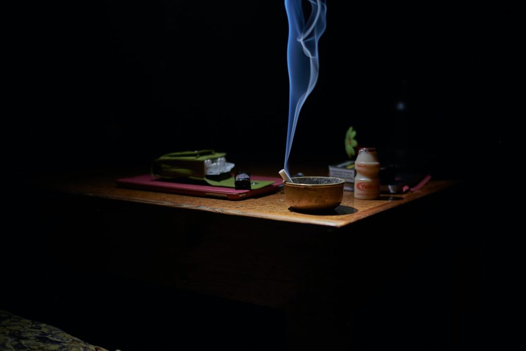 brown ashtray with cigarette casting smoke on table