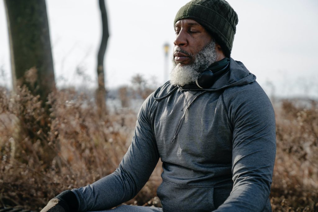 thoughtful black man in activewear meditating in autumn park