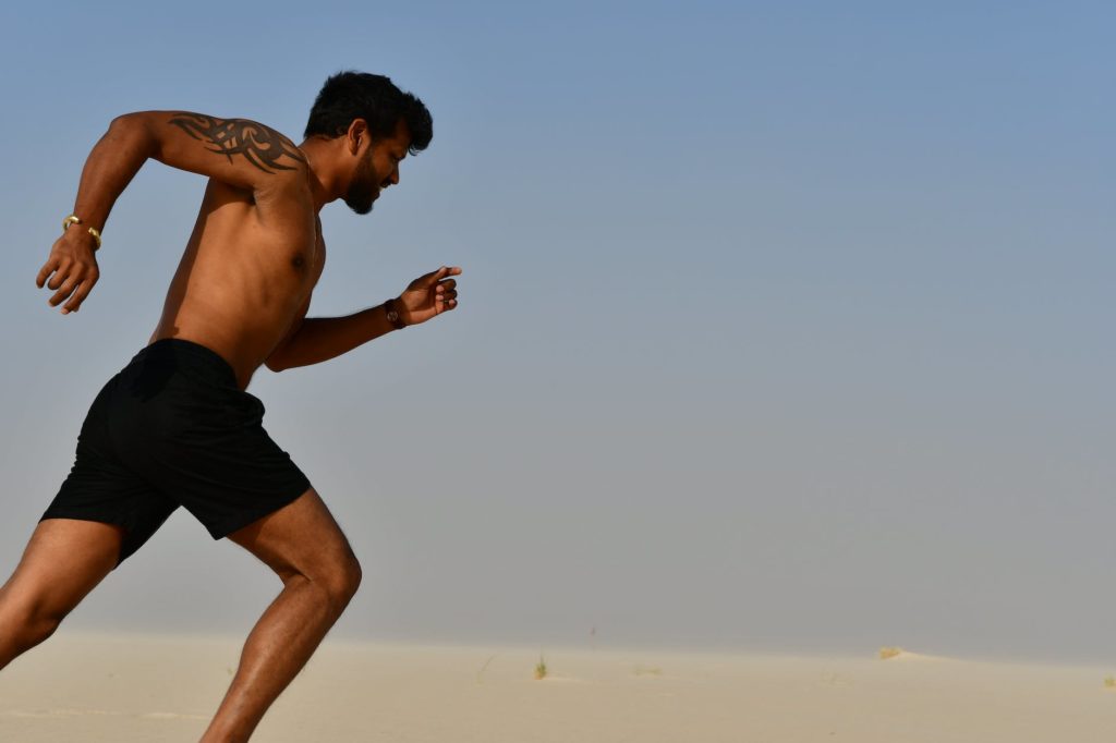 strong shirtless sportsman jogging on bright day