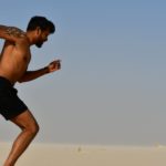 strong shirtless sportsman jogging on bright day