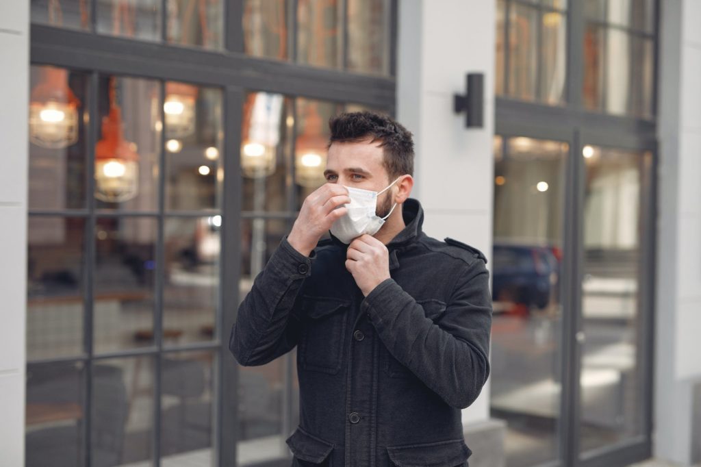 young man in medical mask on urban street during coronavirus pandemic